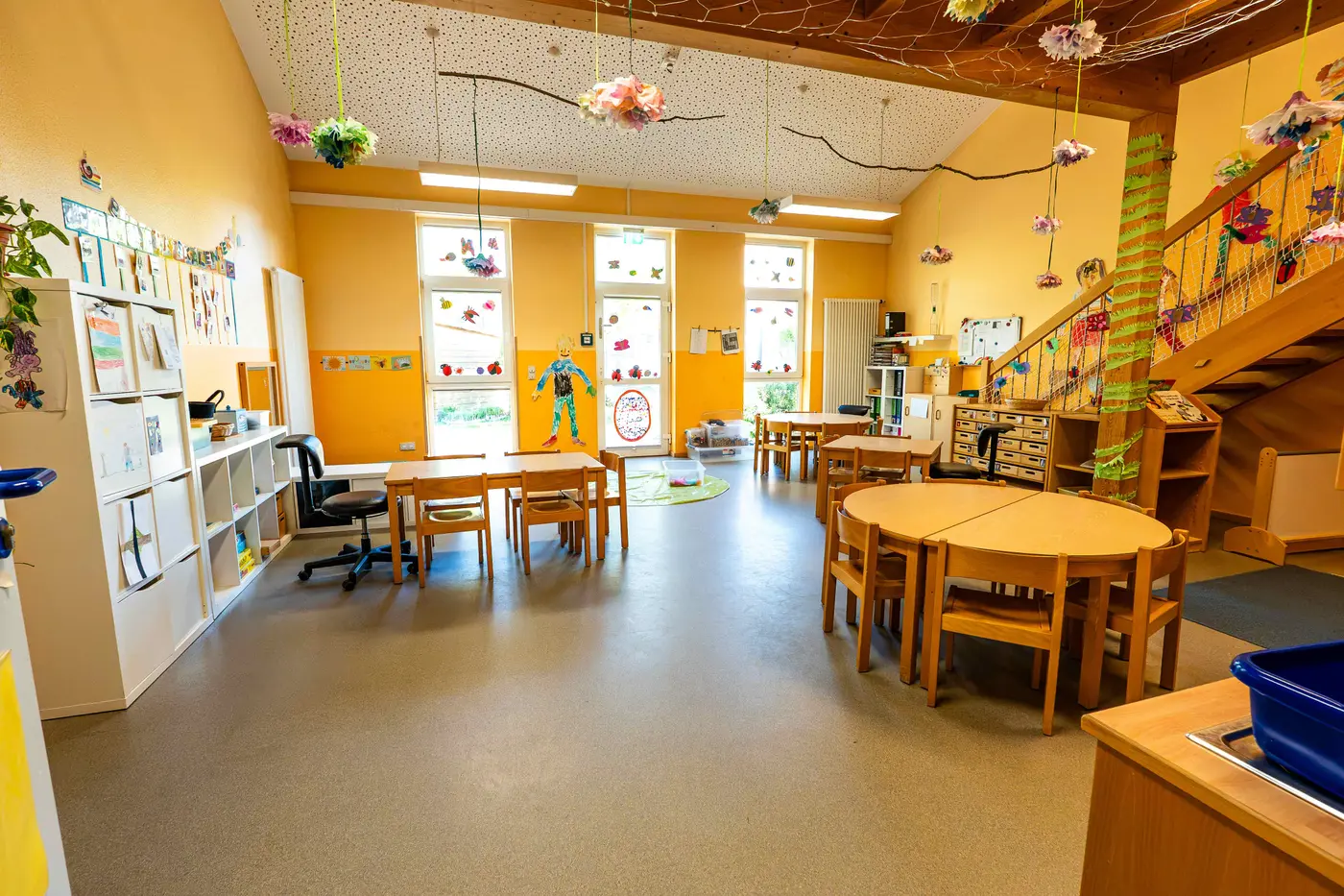 Gruppenraum mit Kindertischen und Hängedekoration in der Kita Schweich